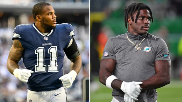 Micah Parsons runs on the field while looking over his shoulder; Tyreek Hill holds one of his arms while looking to the side as well
